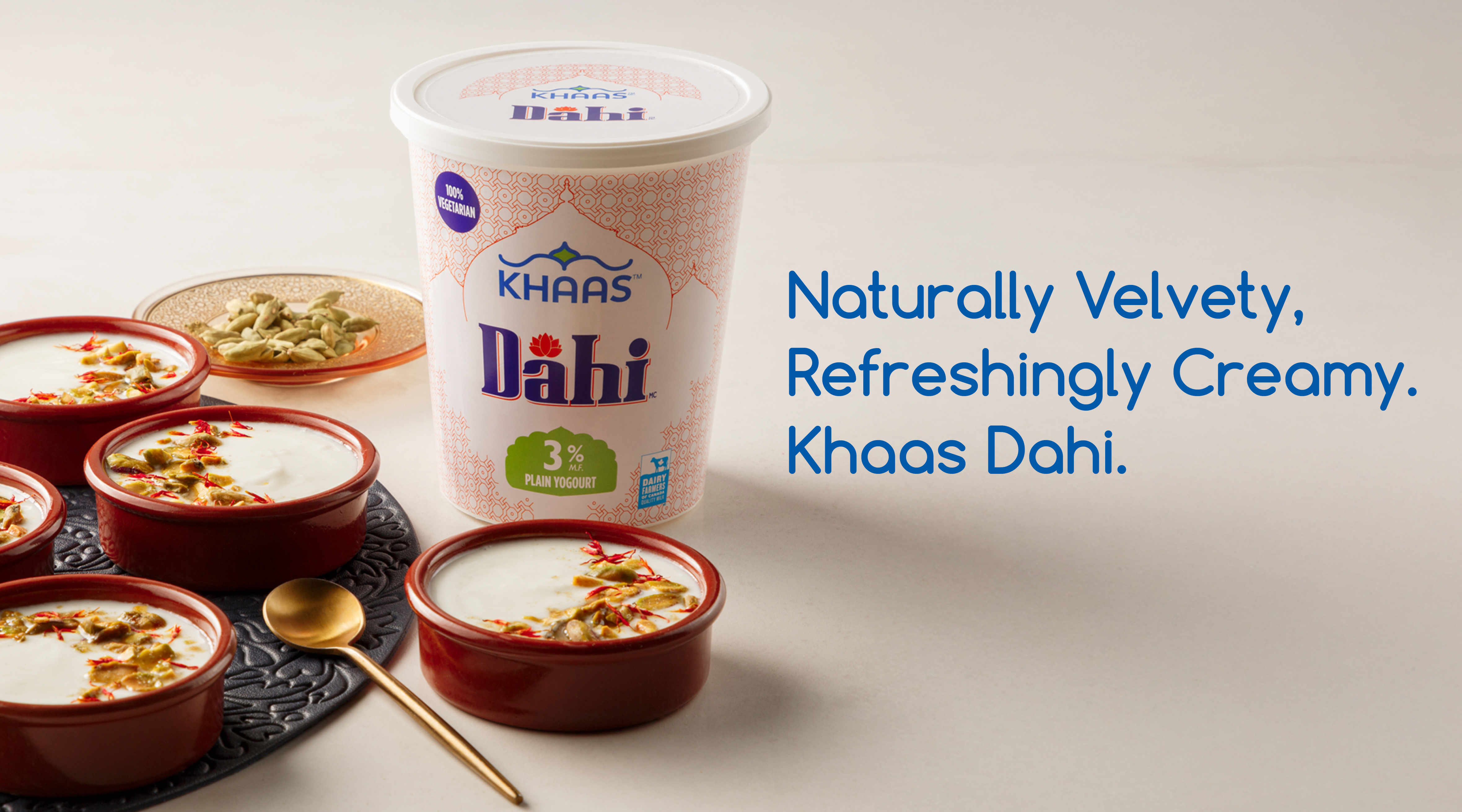 Banner featuring ‘Khaas Dahi 3%’ product packaging shot set against an off-white background. We see an assortment of yogourt dishes in brown earthen bowels and a plate of Cardamom. The headline on the banner reads, “Naturally Velvety, Refreshingly Creamy. Khaas Dahi.”