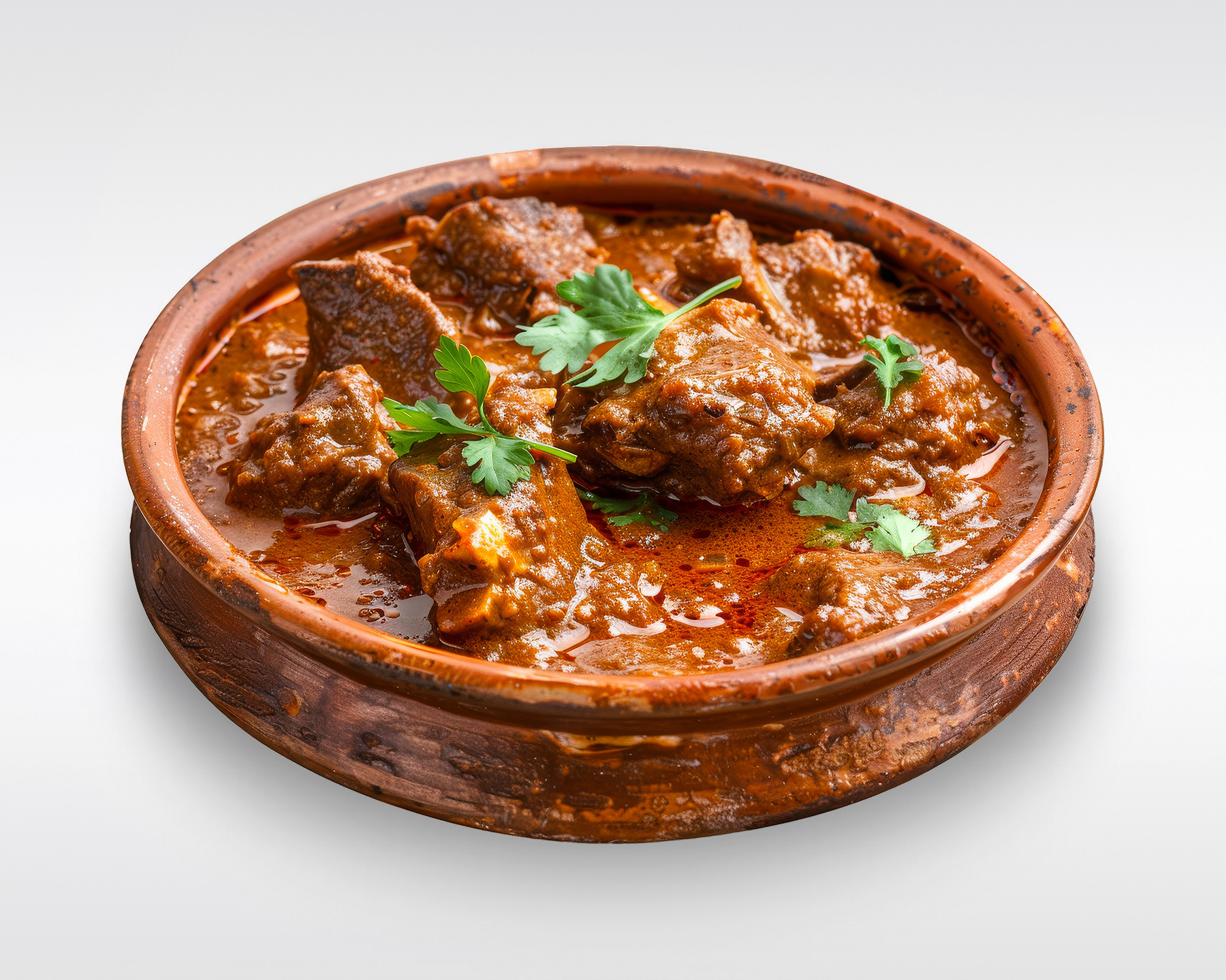 Image of Lamb curry with Cilantro as garnish in a Copper serving vessel.