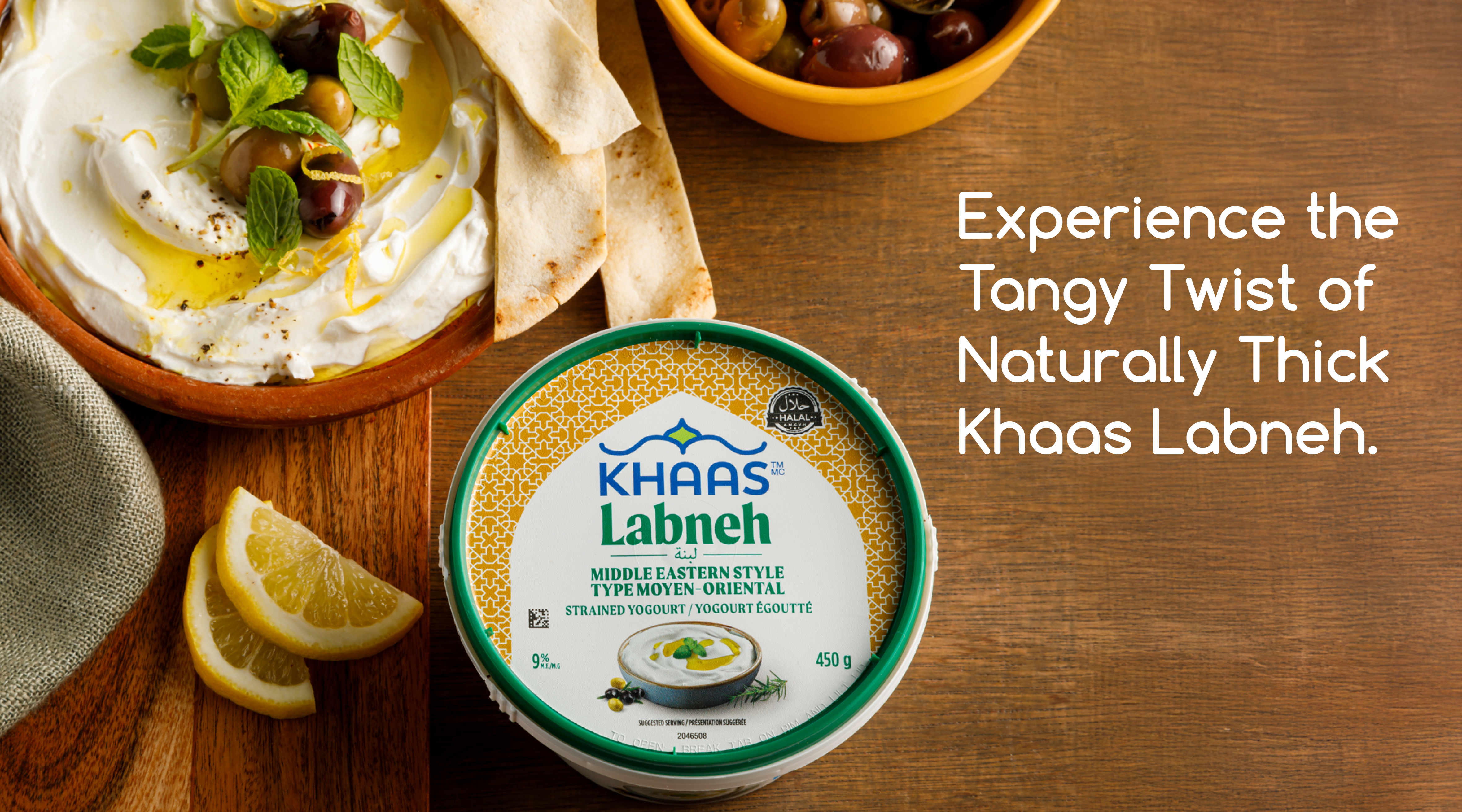 Banner features a bird’s-eye-view shot of ‘Khaas Labneh’. The product is set on a wooden counter top with an assortment of dishes around it that include the labneh dip in a bowel, topped with olives, pita bread sticks and lemon wedges. The headline in this banner reads, “Experience the Tangy Twist of Naturally Thick Khaas Labneh.”